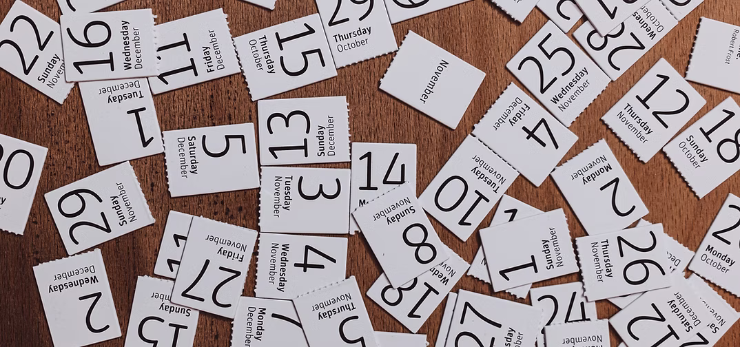 Scattered cutouts of calendar dates on a table.